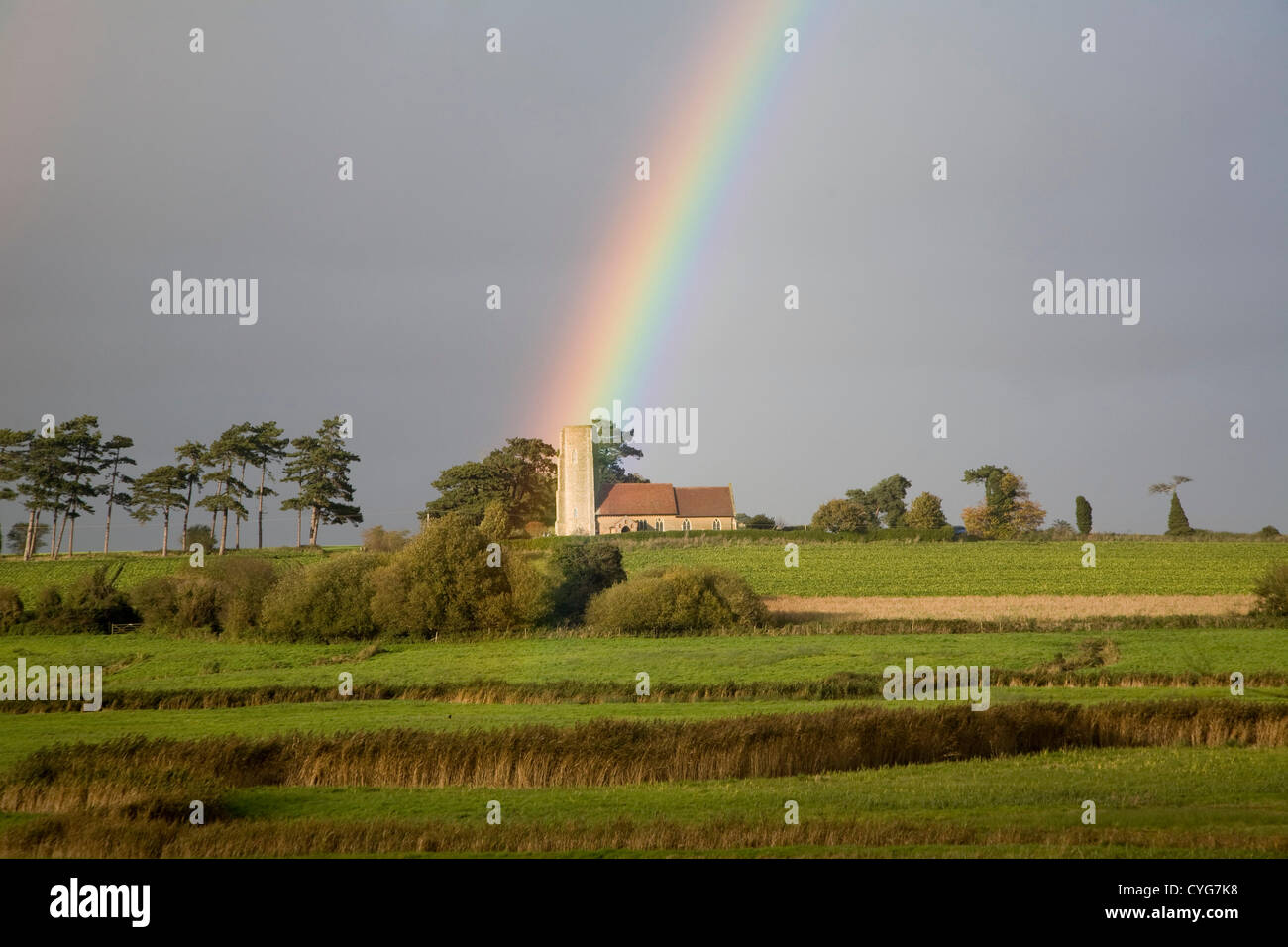 4 novembre 2012 Ramsholt chiesa, Suffolk, Inghilterra ha la sua antica torre rotonda illuminata dalla fine di un arcobaleno. Foto Stock