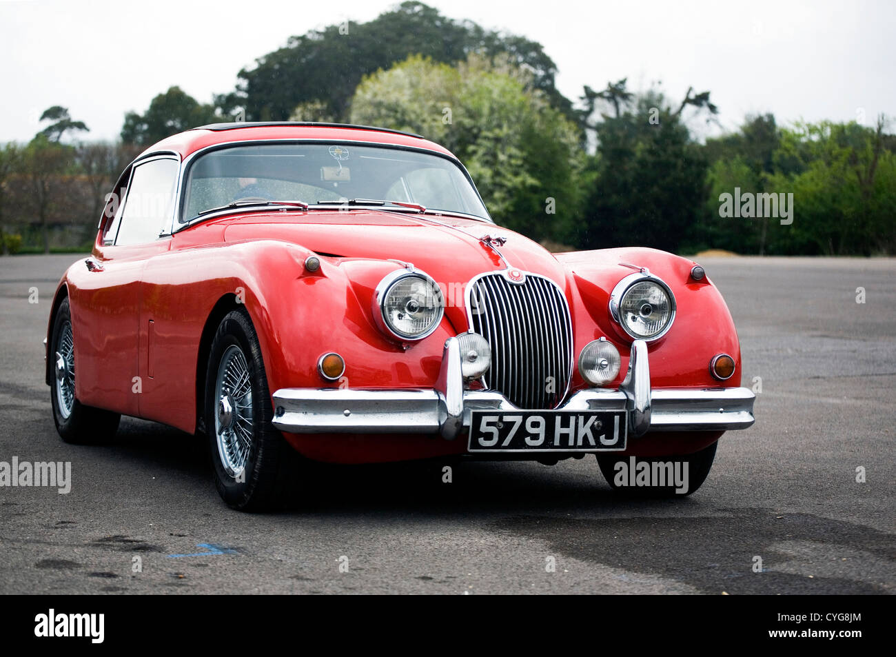 Un classico rosso Jaguar seduto in un vuoto di parcheggio auto Foto Stock