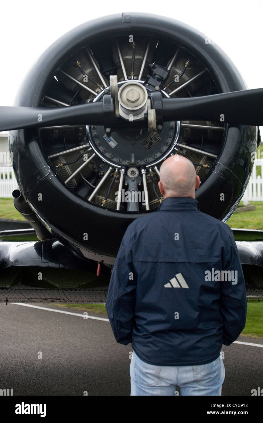 Un uomo in cerca nel motore di un vecchio propulsore piano. Foto Stock