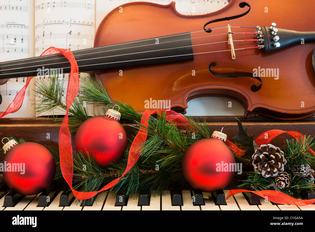Un violino e foglio di musica si siede su un piano che è stato decorato per il Natale. Foto Stock