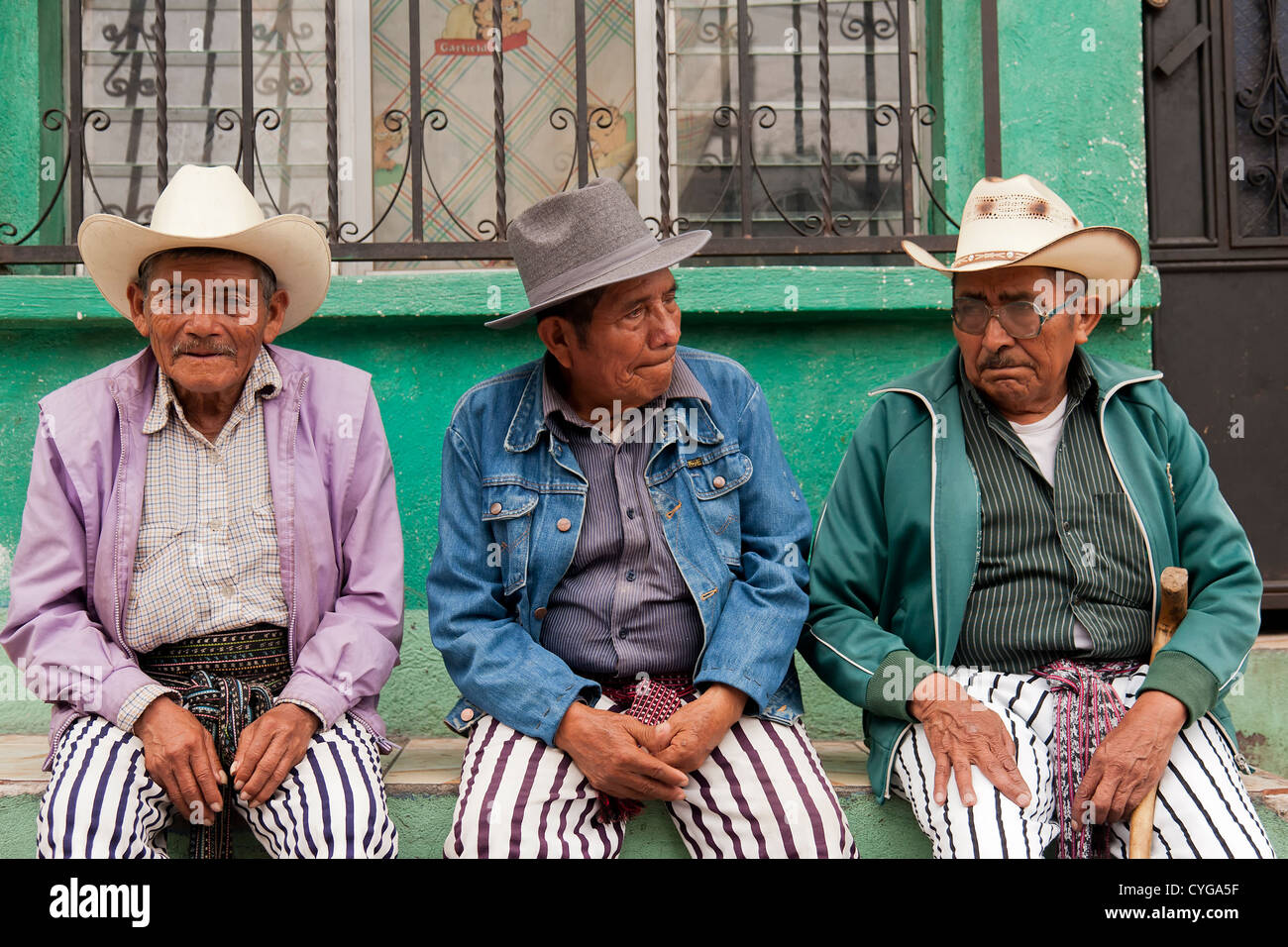 Tre uomini attendono il culto di Maximón, un folk san e di vestire appropriatamente durante le festività di Pasqua a Santiago Atitlan, Guatemala Foto Stock