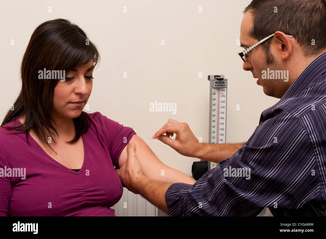 Medico GP si prepara a somministrare una vaccinazione ad un paziente. Foto Stock