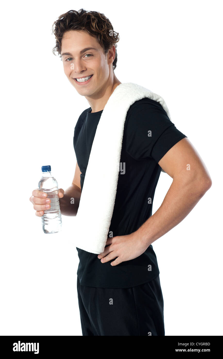Fiducioso giovane ragazzo sportivo guardando a voi come egli si pone con una bottiglia d'acqua Foto Stock