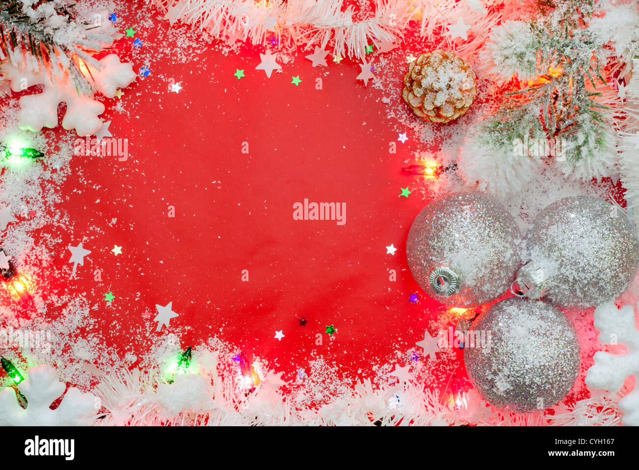 Le luci di Natale confine con baubles e neve su sfondo rosso Foto Stock
