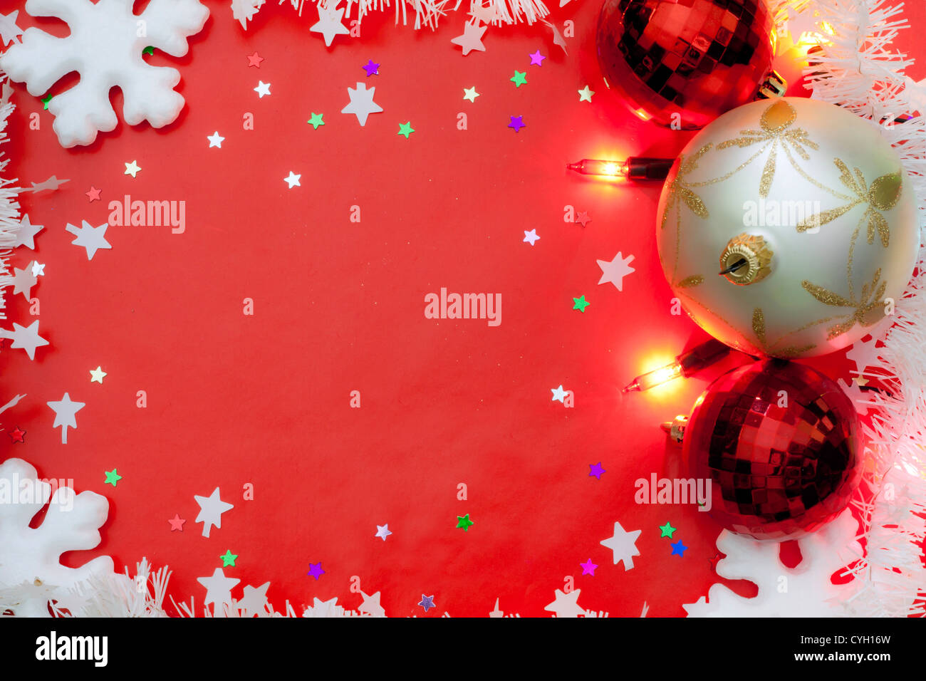 Le luci di Natale confine con baubles e neve su sfondo rosso Foto Stock