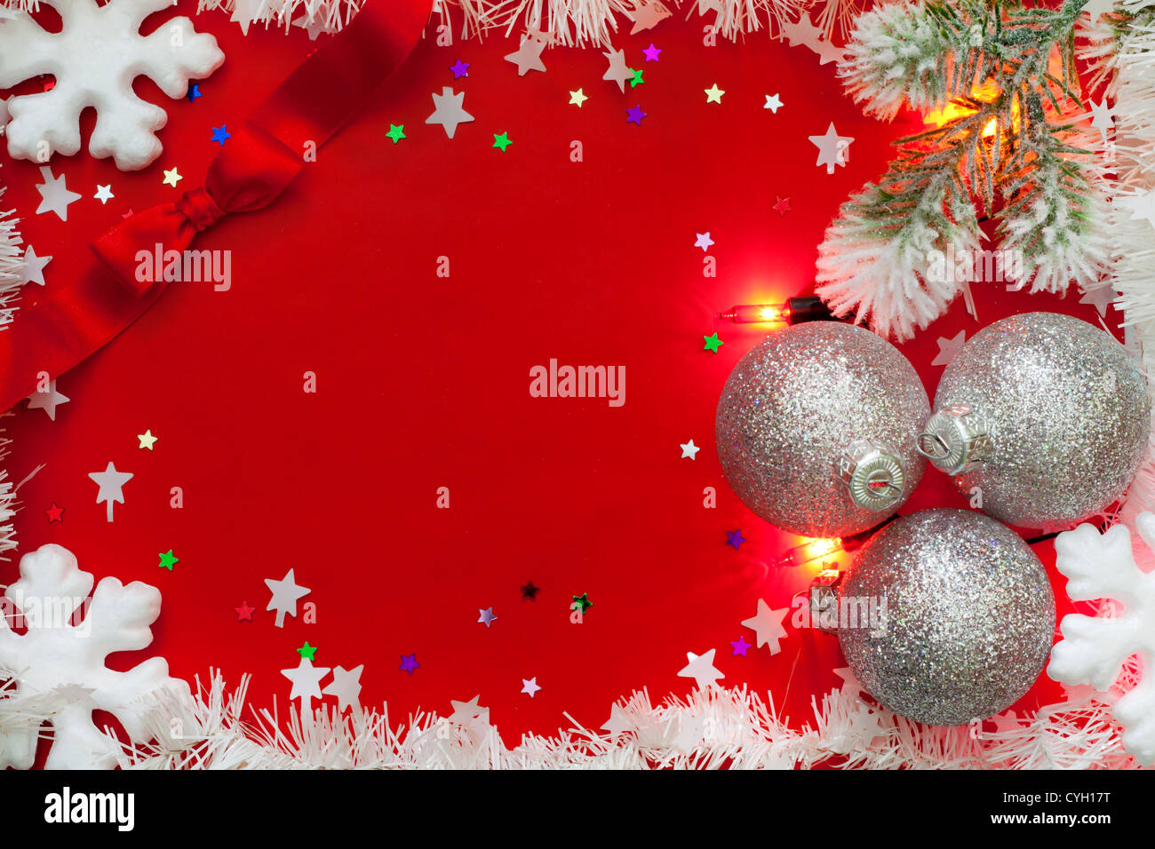 Le luci di Natale confine con baubles e neve su sfondo rosso Foto Stock