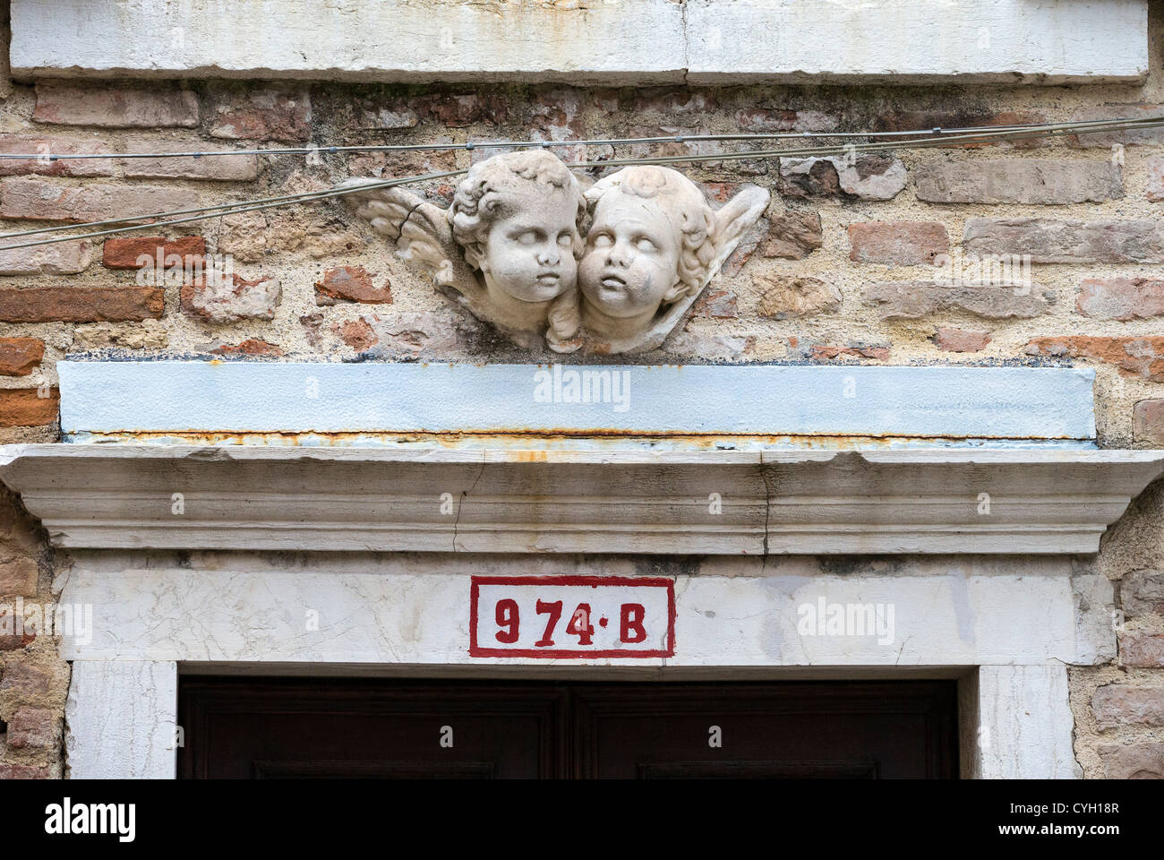 I capi di una coppia di putti alati o cherubini scolpiti sopra l'architrave di una porta a Venezia Foto Stock