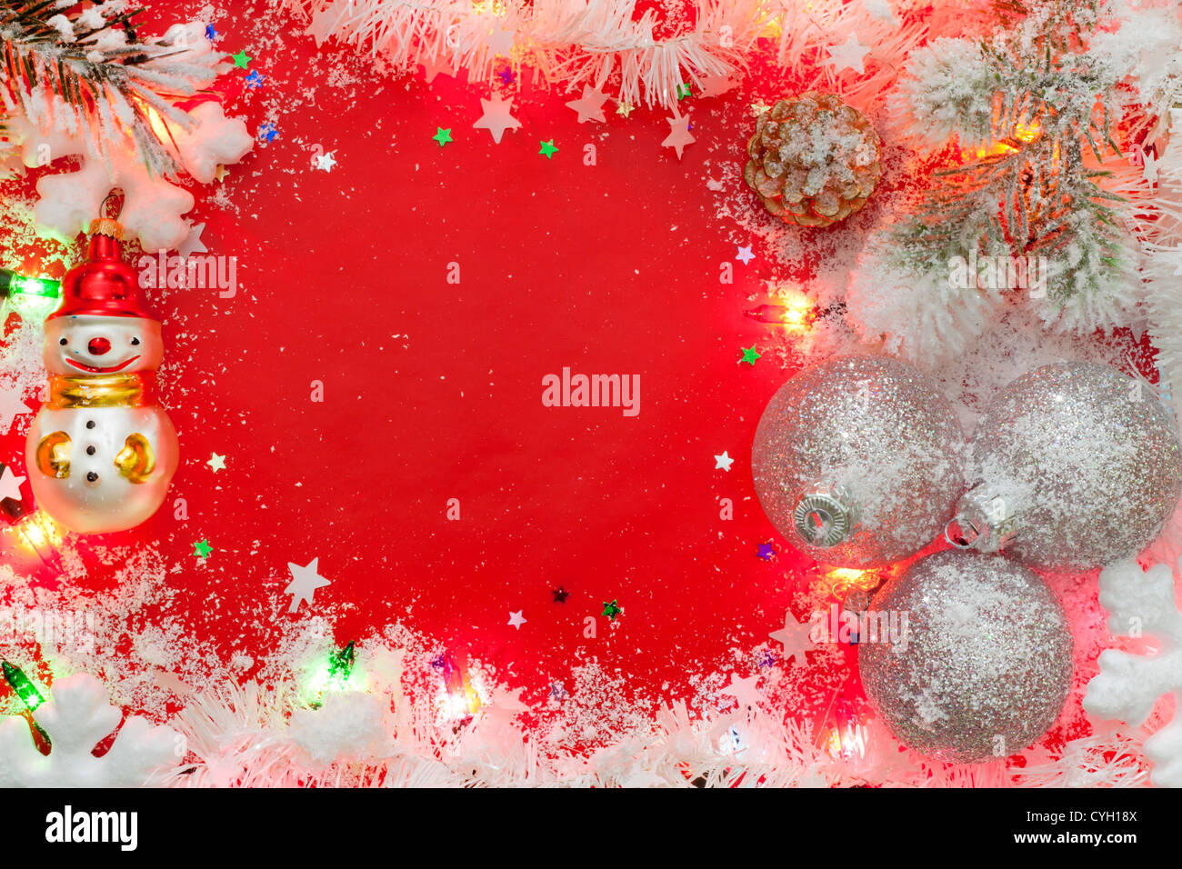 Le luci di Natale confine con baubles e neve su sfondo rosso Foto Stock