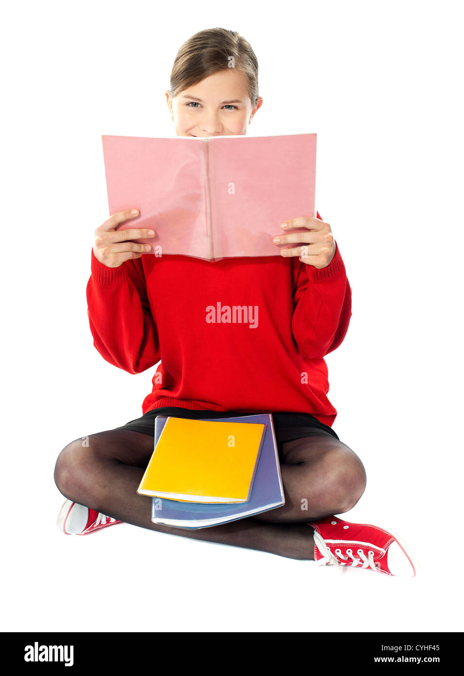 Scuola intelligente ragazza seduta con i libri sul suo grembo e studiando dal suo notebook Foto Stock
