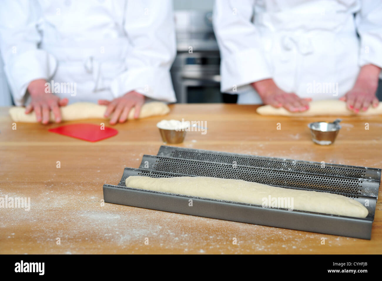 Rotolare la pasta su di un tavolo di legno con le mani. Chef femmina mani Foto Stock
