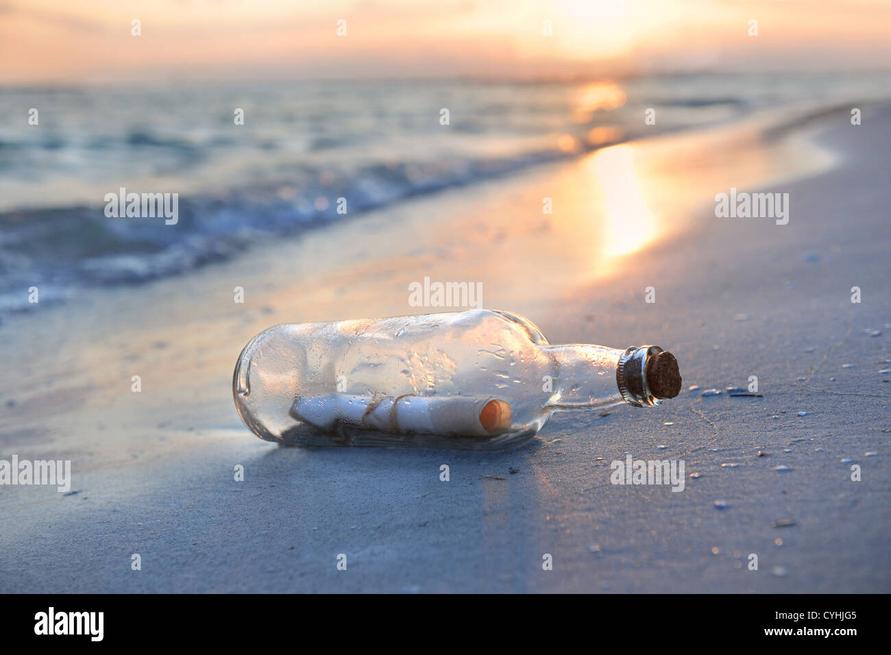 Un messaggio in bottiglia appoggiata a terra durante il tramonto Foto Stock