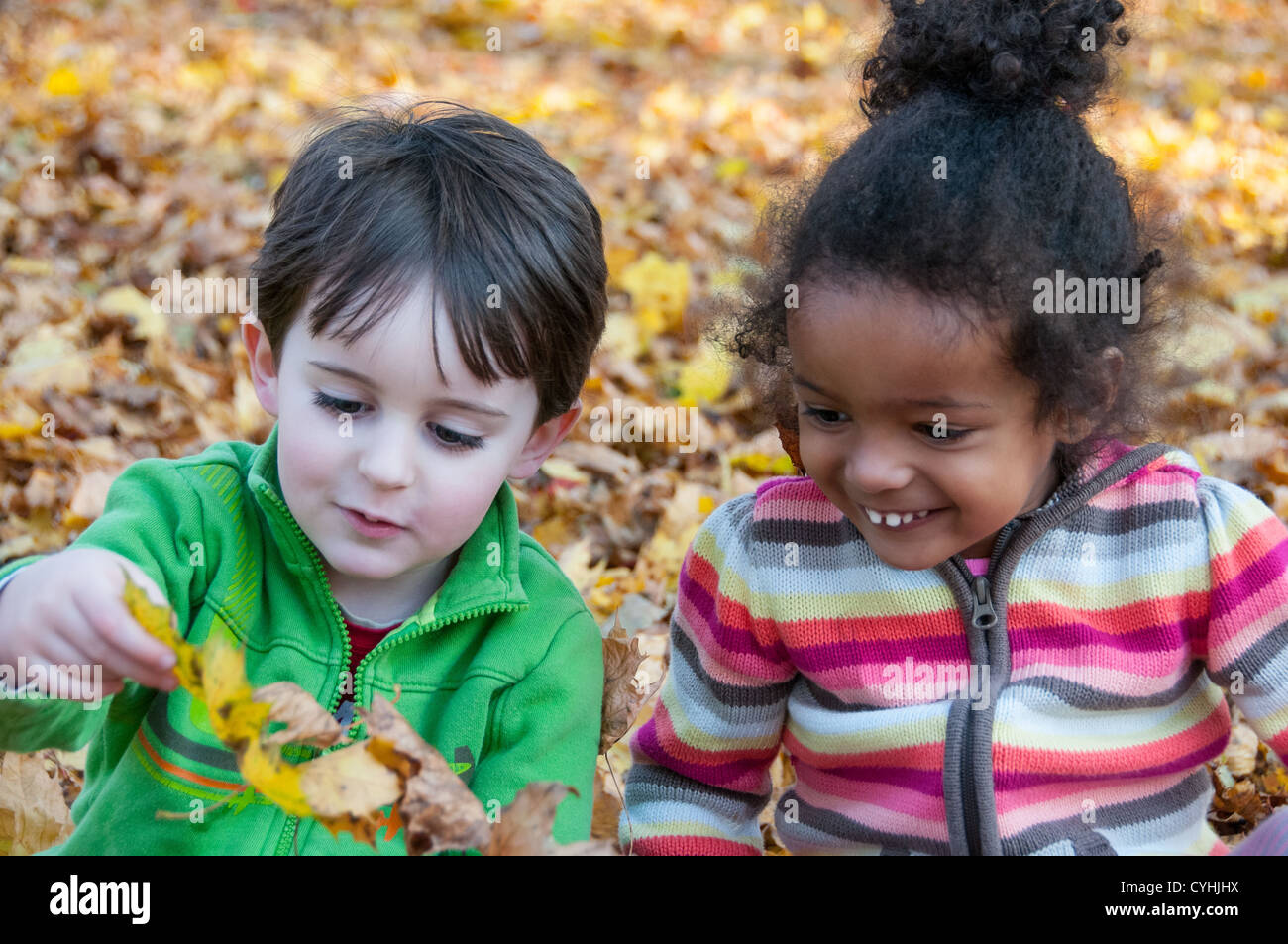 Due bambini che giocano in foglie Foto Stock