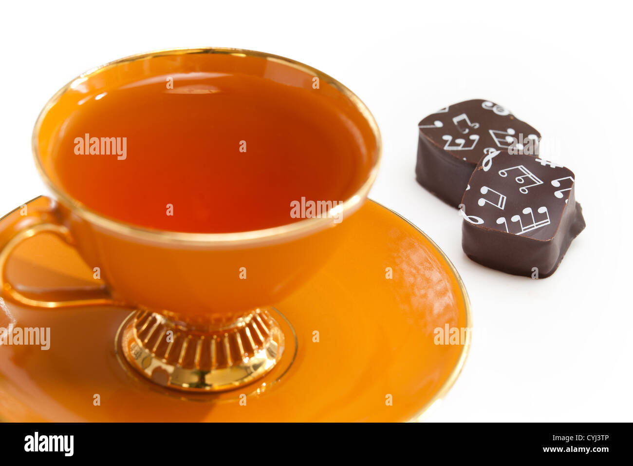 Orange tazza da tè a tea party con nota musicale di cioccolato con banconote stampate su di essi. Foto Stock