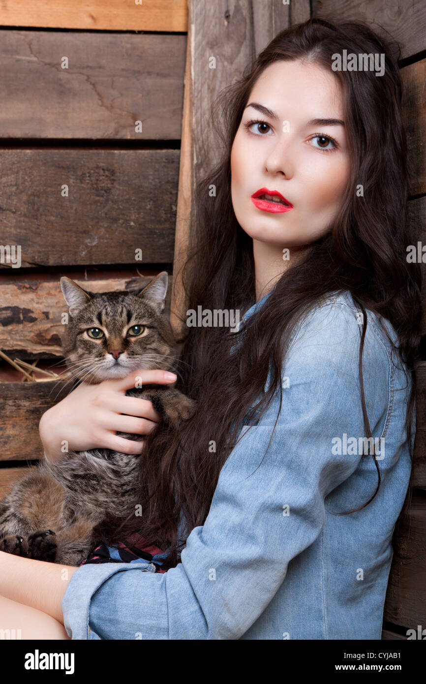 Ritratto di una donna con un gatto sullo sfondo delle pareti di legno. Foto Stock