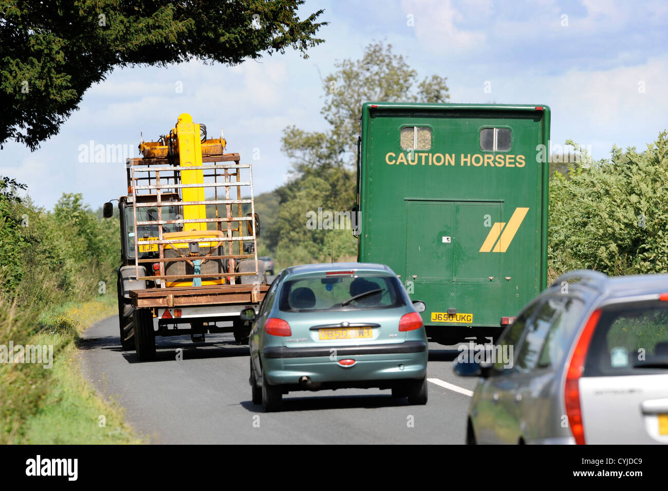 Un box per cavallo supera un veicolo agricolo su una strada nel GLOUCESTERSHIRE REGNO UNITO Foto Stock