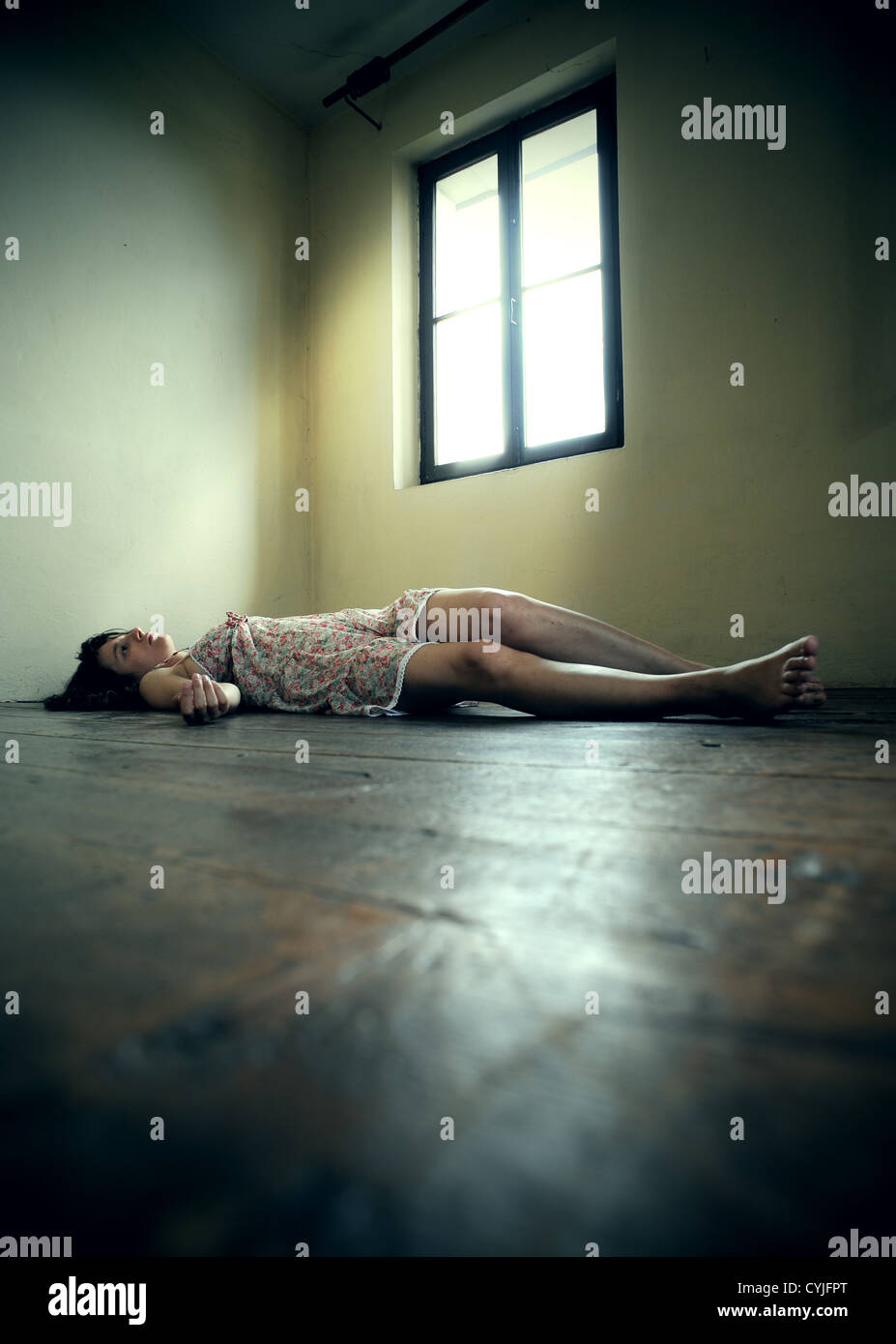 Dead donna sdraiata sul pavimento di legno. Camera vuota Foto Stock