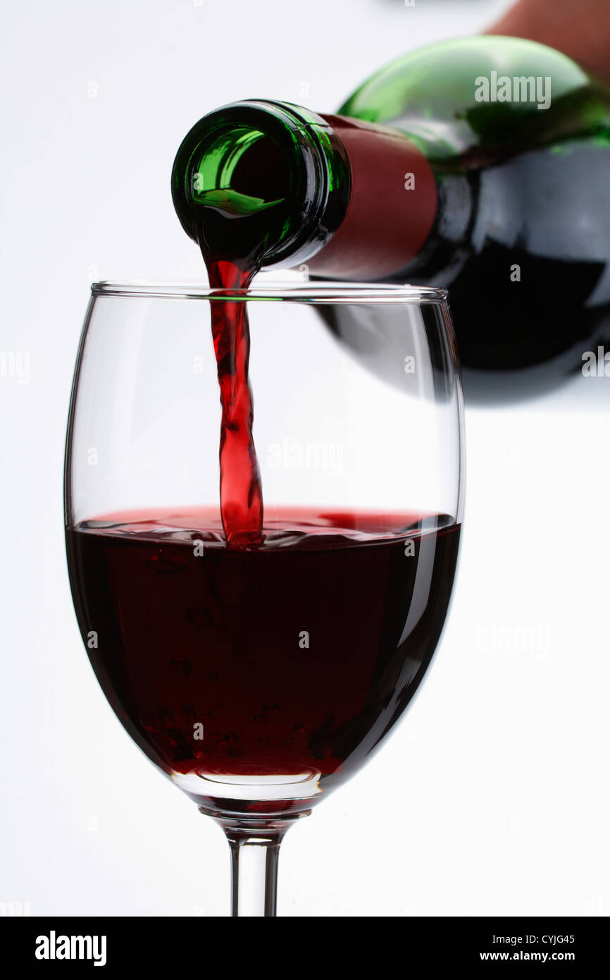 Vino rosso versare in un bicchiere su sfondo bianco Foto Stock