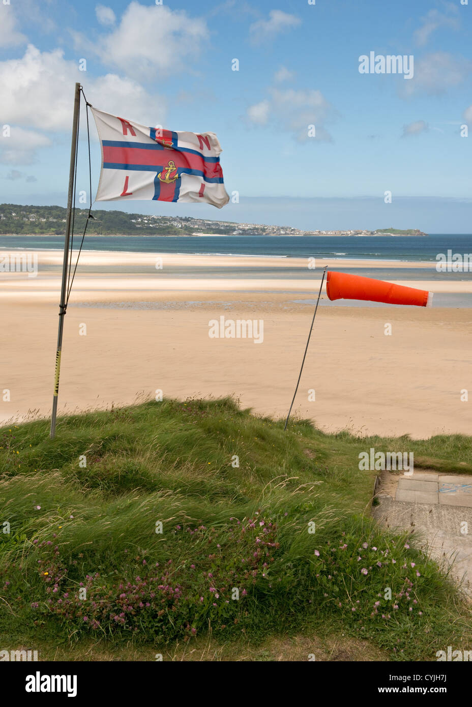 Bandiera RNLI svolazzanti nella brezza di mare su ampi sabbie della spiaggia di Hayle, Cornwall Foto Stock