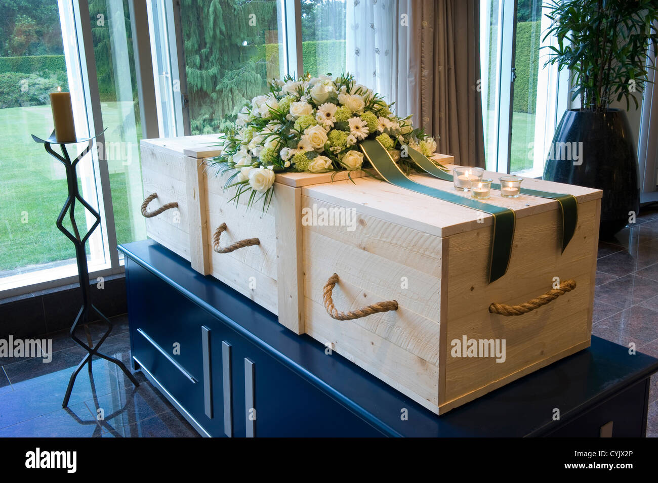 Una bara in un crematorio con un omaggio floreale su di esso Foto Stock