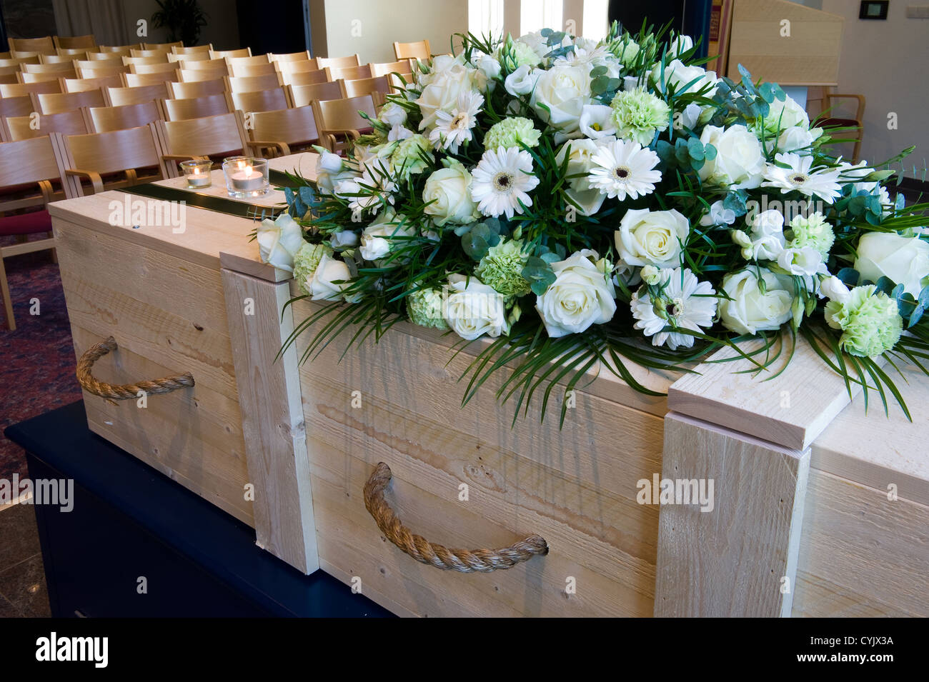 Una bara in un crematorio con un omaggio floreale Foto Stock