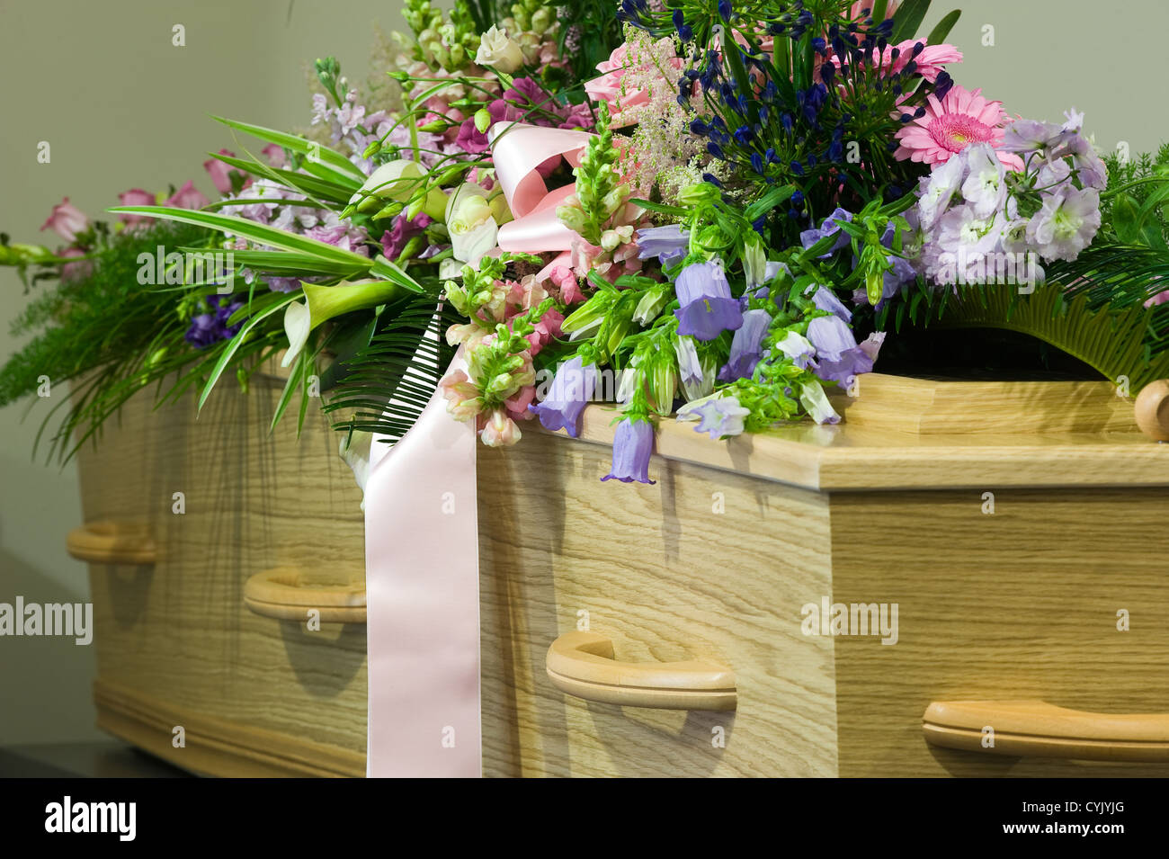 Una bara in un obitorio con un omaggio floreale Foto Stock