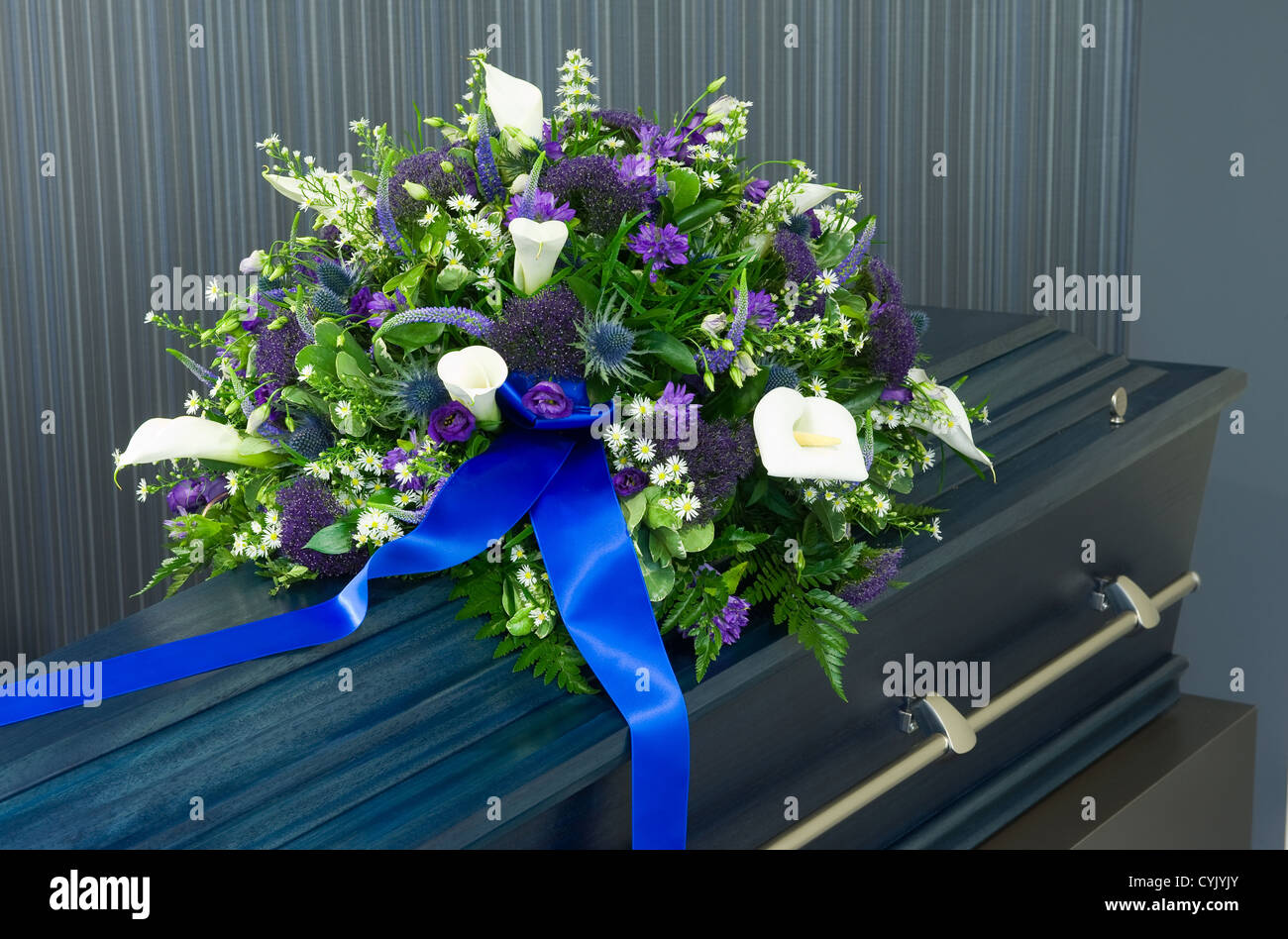 Una bara blu in un obitorio con un omaggio floreale Foto Stock