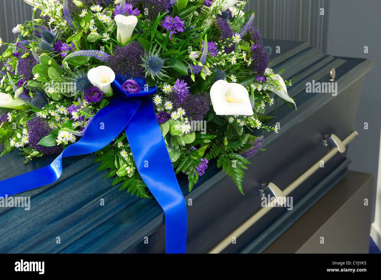 Una bara blu in un obitorio con un omaggio floreale Foto Stock