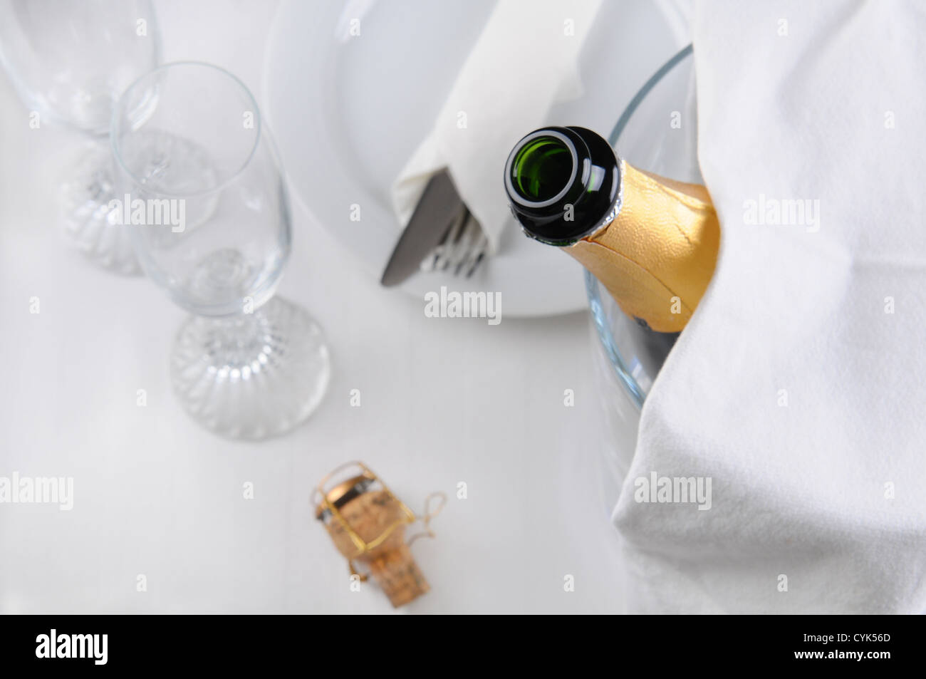 Aprire una bottiglia di champagne in un secchiello per il ghiaccio su un tavolo per la cena. Profondità di campo. Foto Stock