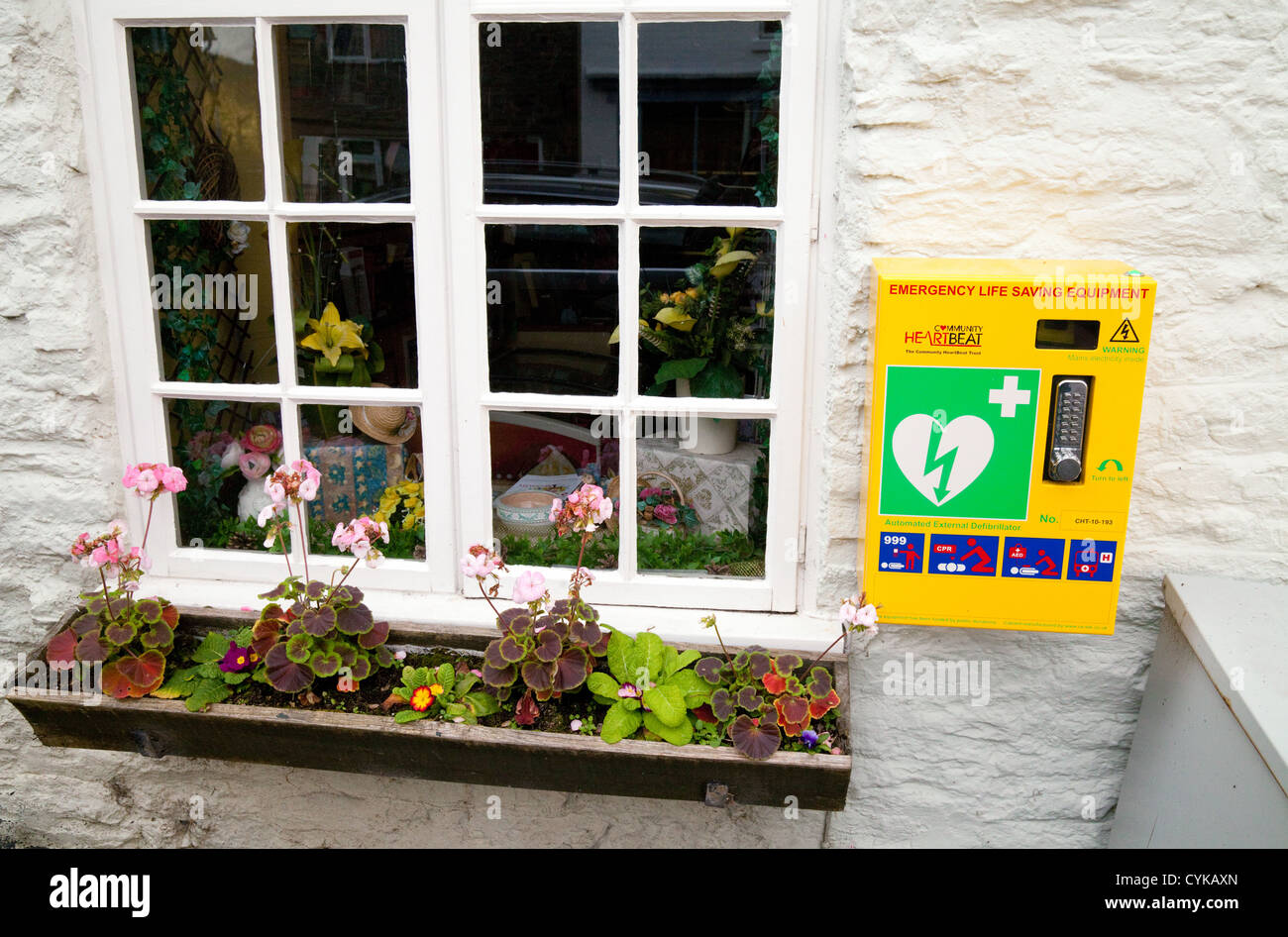 Un cuore cardiaco defibrillatore disponibile al pubblico sulla parete in villaggio Clun nello Shropshire, Regno Unito Foto Stock