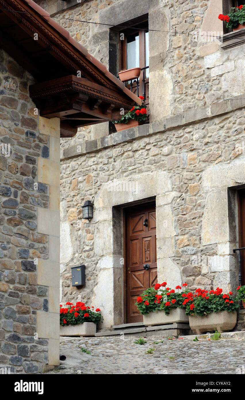 Strada di ciottoli con il rosso dei gerani. Cillorigo de Liébana, Cantabria, Spagna. Foto Stock