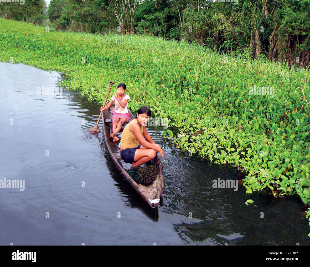 Due ragazze nativi pagaiare in canoa lungo il fiume del Amazon in Brasile Foto Stock