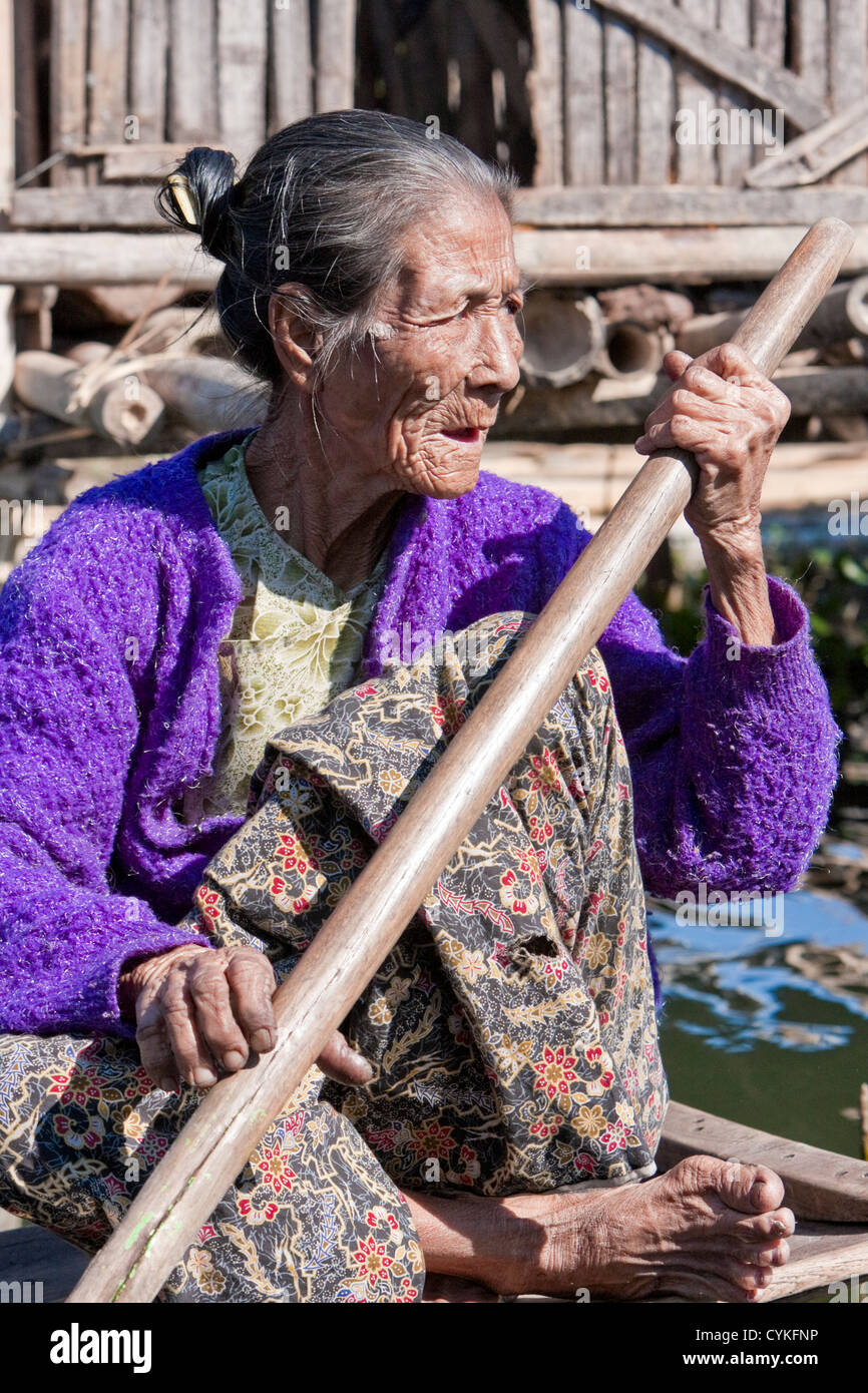 Myanmar Birmania. Vecchia donna Intha Paddling la sua barca, Lago Inle, Stato di Shan. Foto Stock