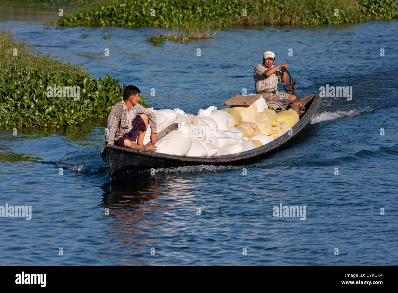 Myanmar Birmania. Due uomini in canoa il trasporto di sacchi di riso, Lago Inle, Stato di Shan. Foto Stock