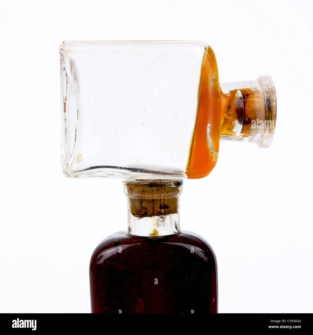 Esclusivo flacone in vetro vintage con design angolare e liquido ambrato visualizzato su uno sfondo pulito Foto Stock Esclusivo flacone in vetro vintage con design angolare e liquido ambrato visualizzato su uno sfondo pulito Foto Stock