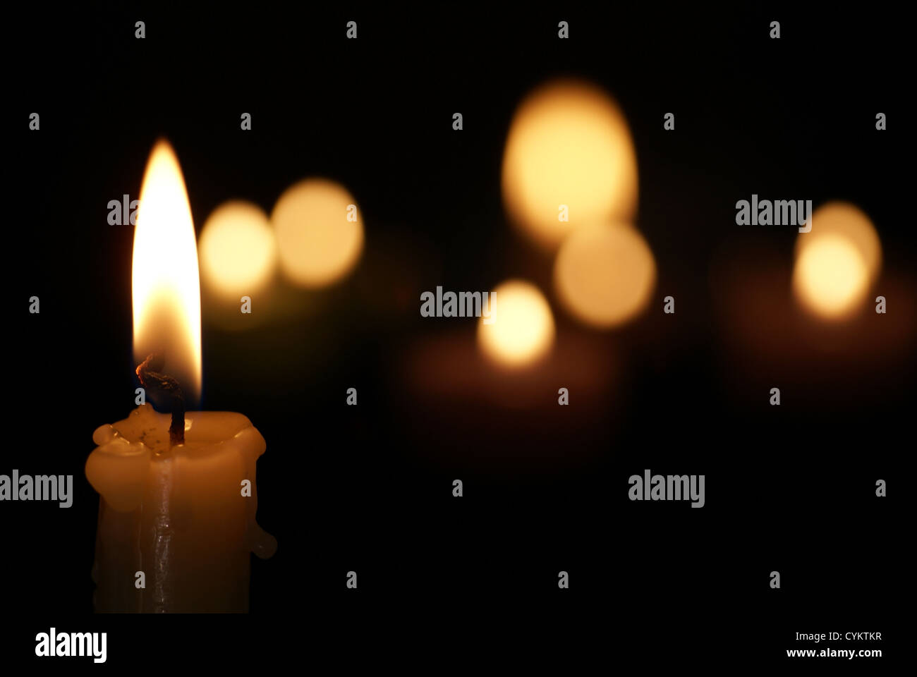 Una candela che brucia con pochi come sfondo Foto Stock