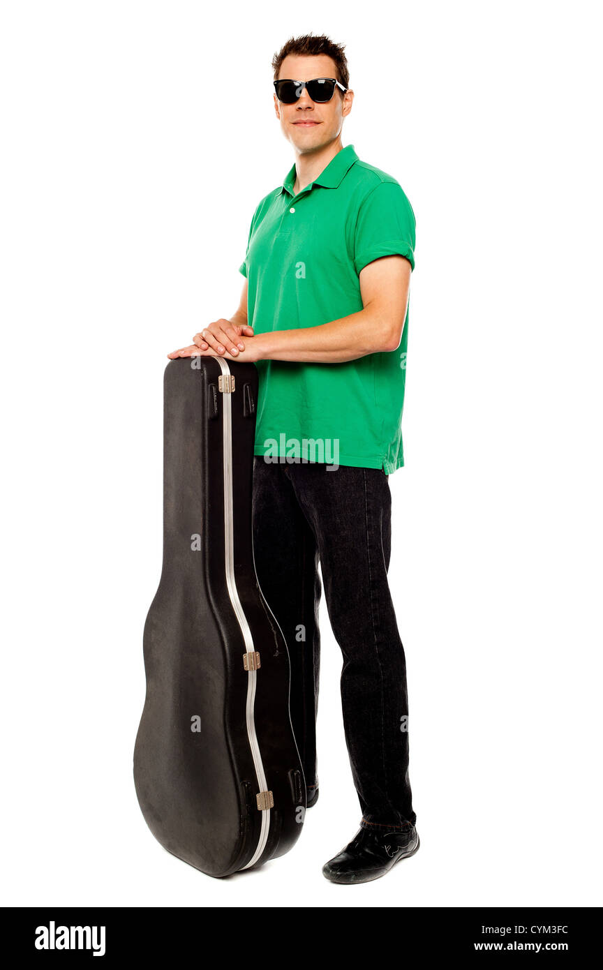 A piena lunghezza shot di giovani alla moda uomo in posa con la chitarra caso su bianco Foto Stock
