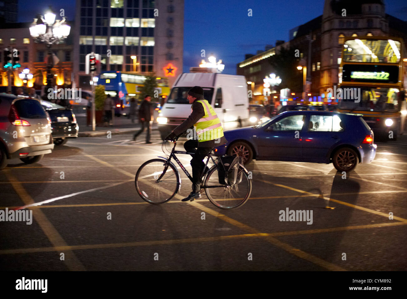 Uomo che indossa alta vis vest in bicicletta nel traffico cittadino del centro durante il periodo invernale scura sera rushhour Rush Hour centro della città di Dublino Repubblica di Irlanda Foto Stock