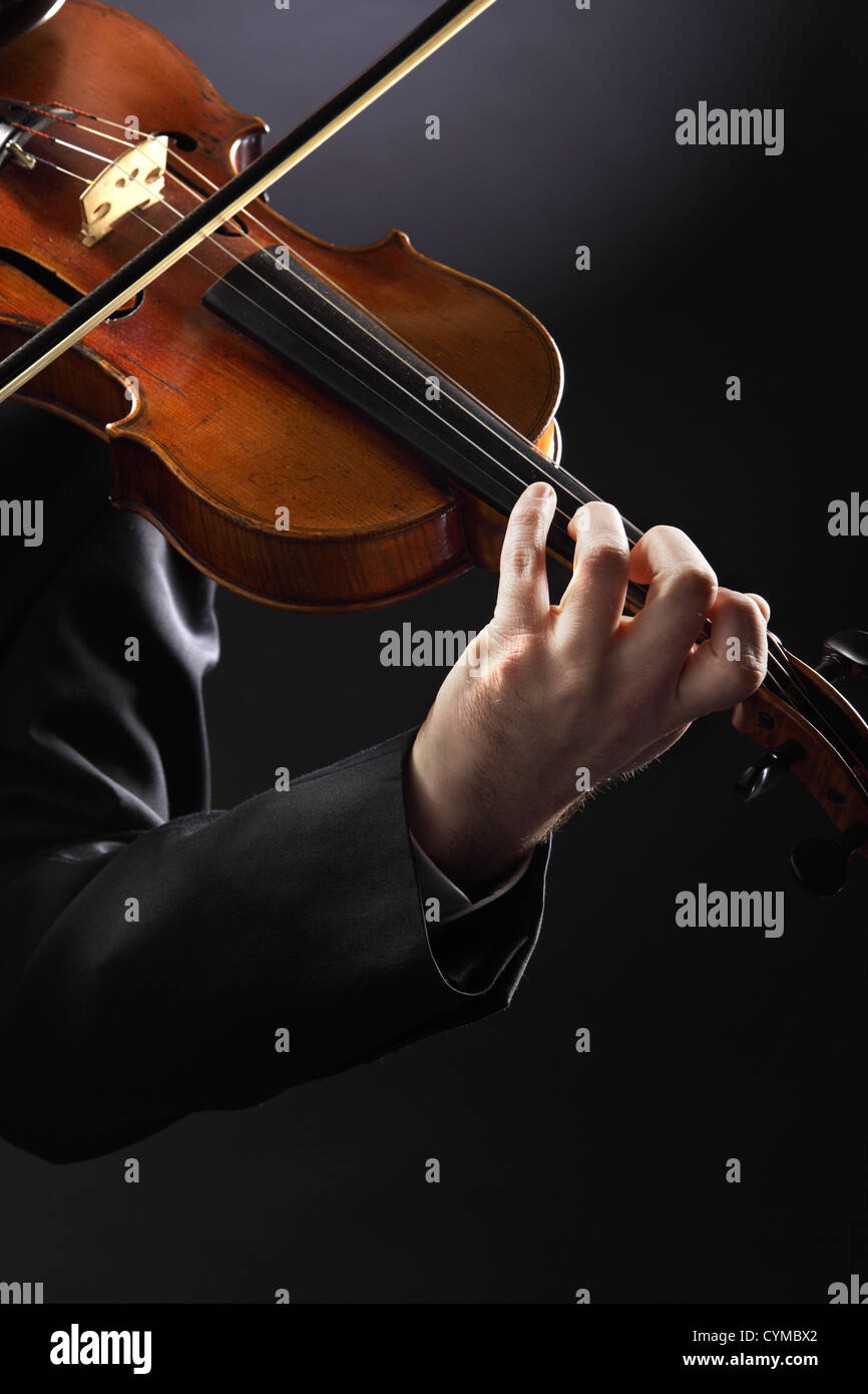 Il violinista: musicista suona il violino su sfondo scuro Foto Stock