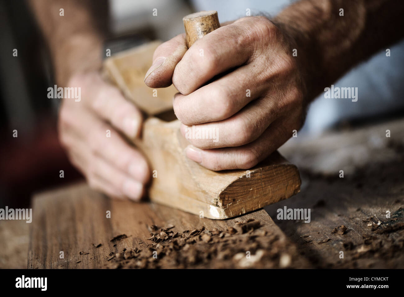 Le mani di un falegname spianare un asse di legno con un piano a mano Foto Stock