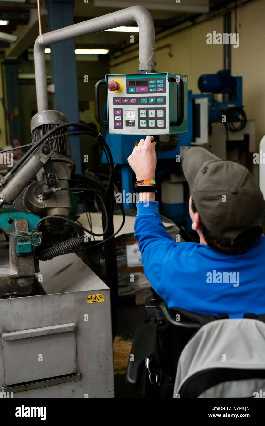 Uomo con disabilità azionato una macchina industriale Foto Stock