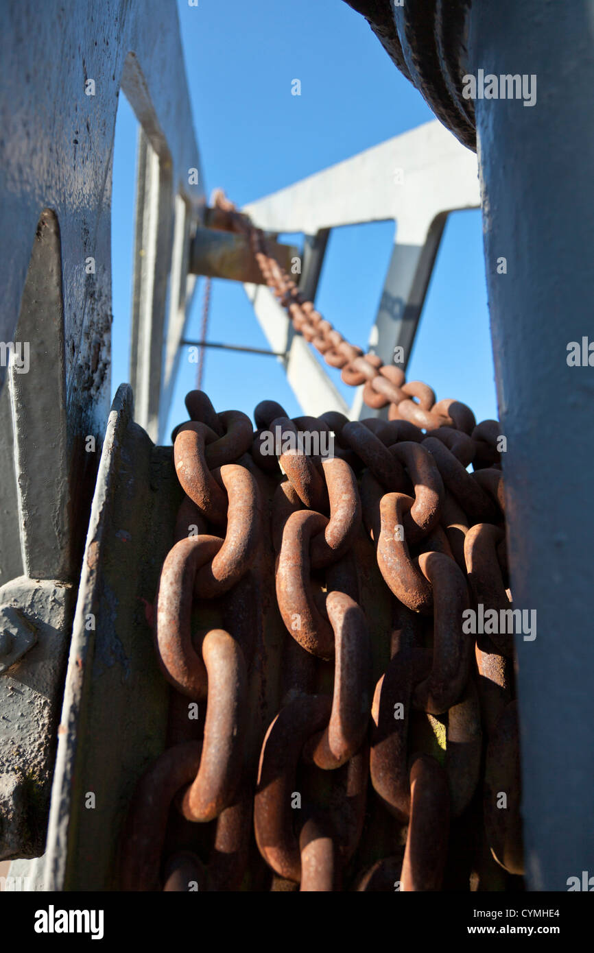 Rusty per impieghi pesanti montate a catena in piccole vecchie banchine laterali, gru di scarico per le piccole imbarcazioni e navi. Foto Stock