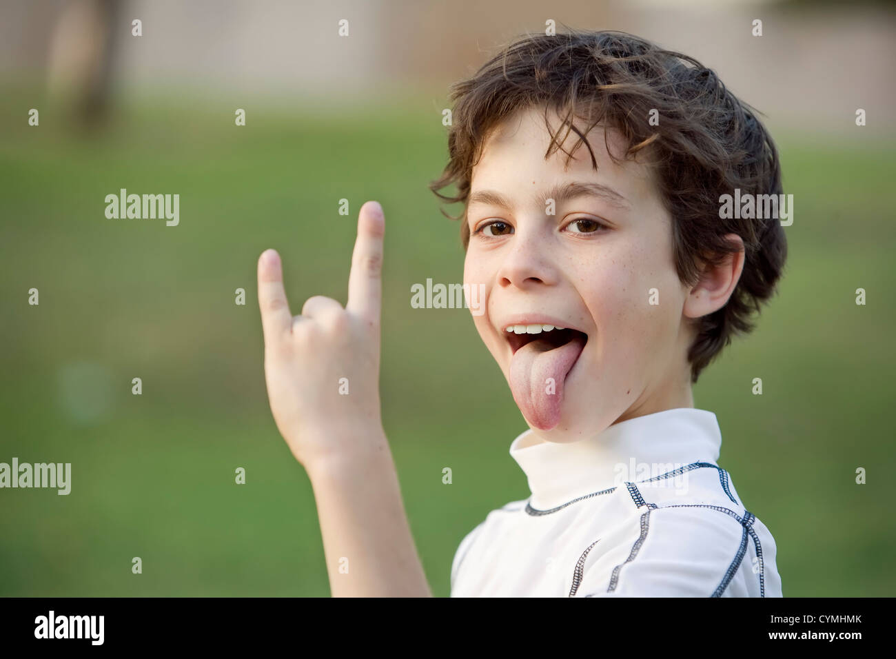 Ragazzo spuntavano la sua lingua e facendo una bull horn gesto con la mano Foto Stock