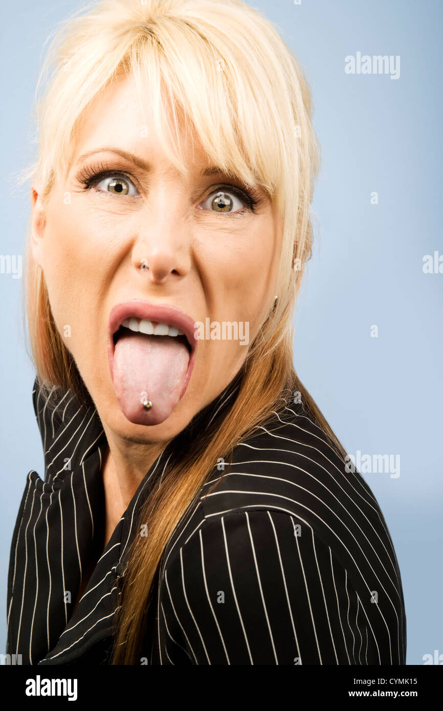 La donna in un pinstriped suit attaccare fuori la sua linguetta forata Foto Stock
