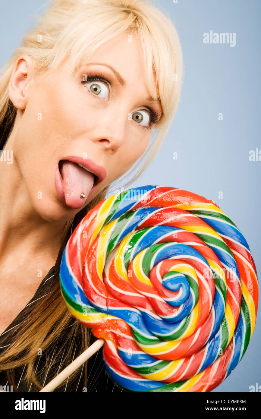 Donna con una linguetta forata leccare un grande lecca-lecca colorati Foto Stock