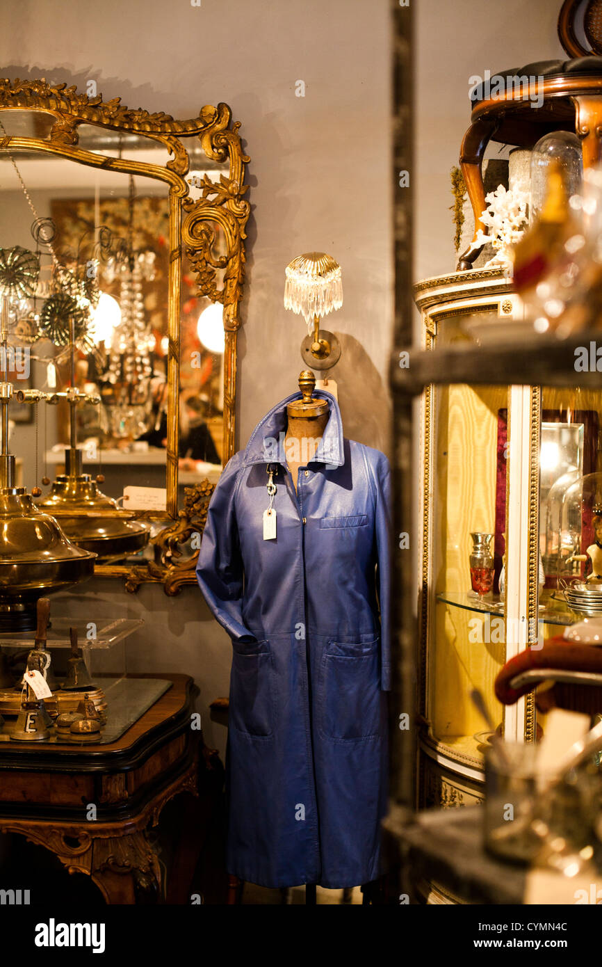 Un blu giacca di pelle si distingue in un angolo di un negozio pieno di mobili d'oro. Foto Stock