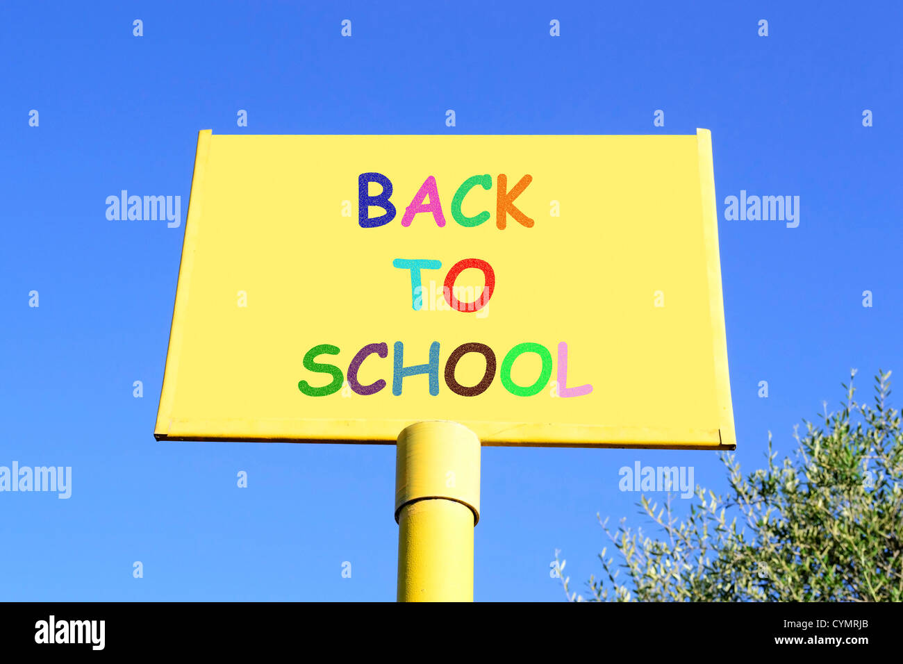 Si torna a scuola la scrittura su un segno giallo sotto un cielo blu chiaro Foto Stock