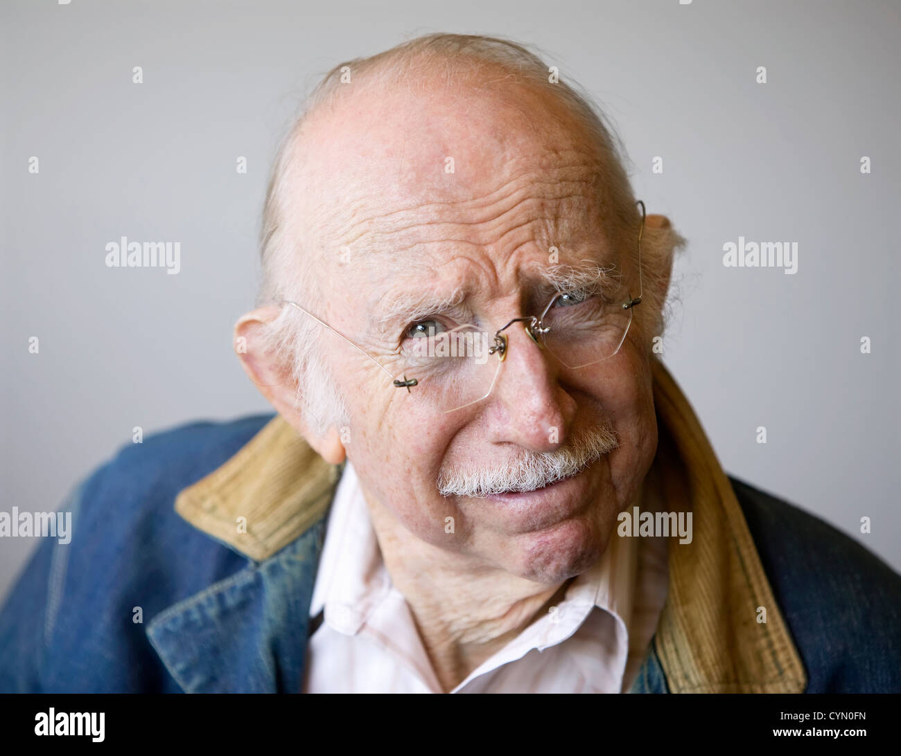 Ritratto di un anziano che indossa occhiali e un jean jacket in studio. Foto Stock