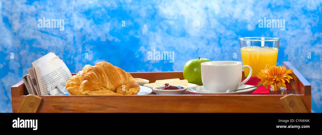 La deliziosa prima colazione sul vassoio costituito da caffè, succo di arancia, succo di mela, croissant, marmellata e burro Foto Stock
