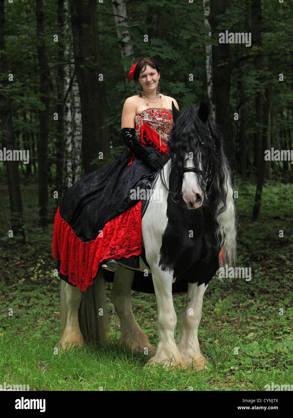 La donna in un bellissimo vecchio stile medievale abiti sul tinker a cavallo nei boschi Foto Stock