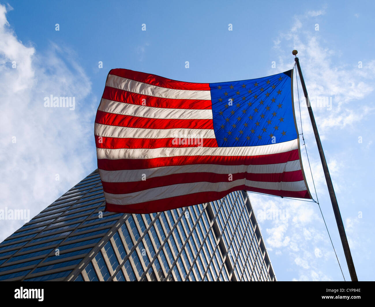 Bandiera americana agitando contro un grattacielo e un cielo blu. Foto Stock